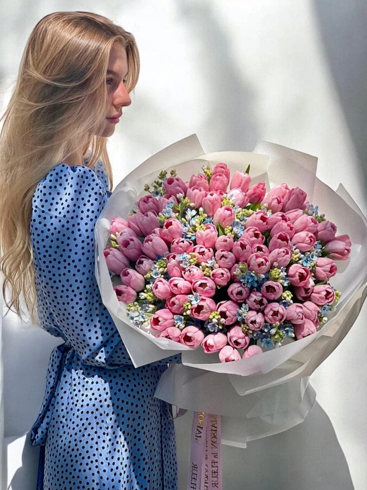 junge Frau hat einen wunderschönen großen Strauß aus rosa Tulpen