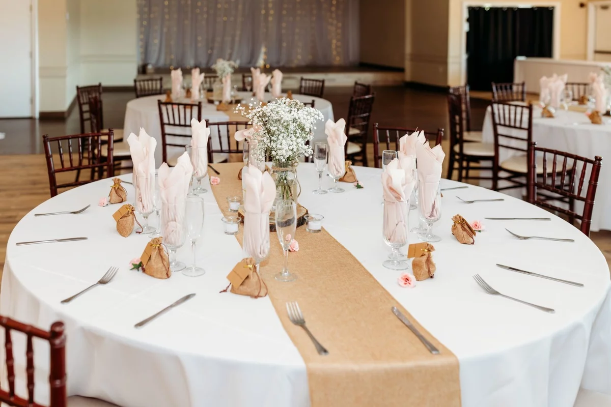 runder Tisch - weiße Decke mit Tischläufer in der Mitte Servietten und Geschänke für Hochzeitsgäste