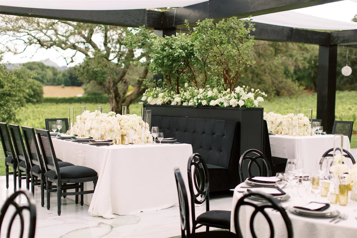 stilvolle Hochzeit Gedecke - weiße Tischdecke und Blumen, schwarzes Geschirr und schwarze Stühle