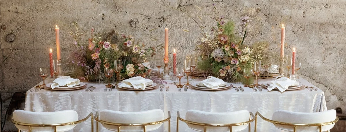 weiße Tischdecke und weiße Stühle - bunte Blumenarrangements und brennende Kerzen