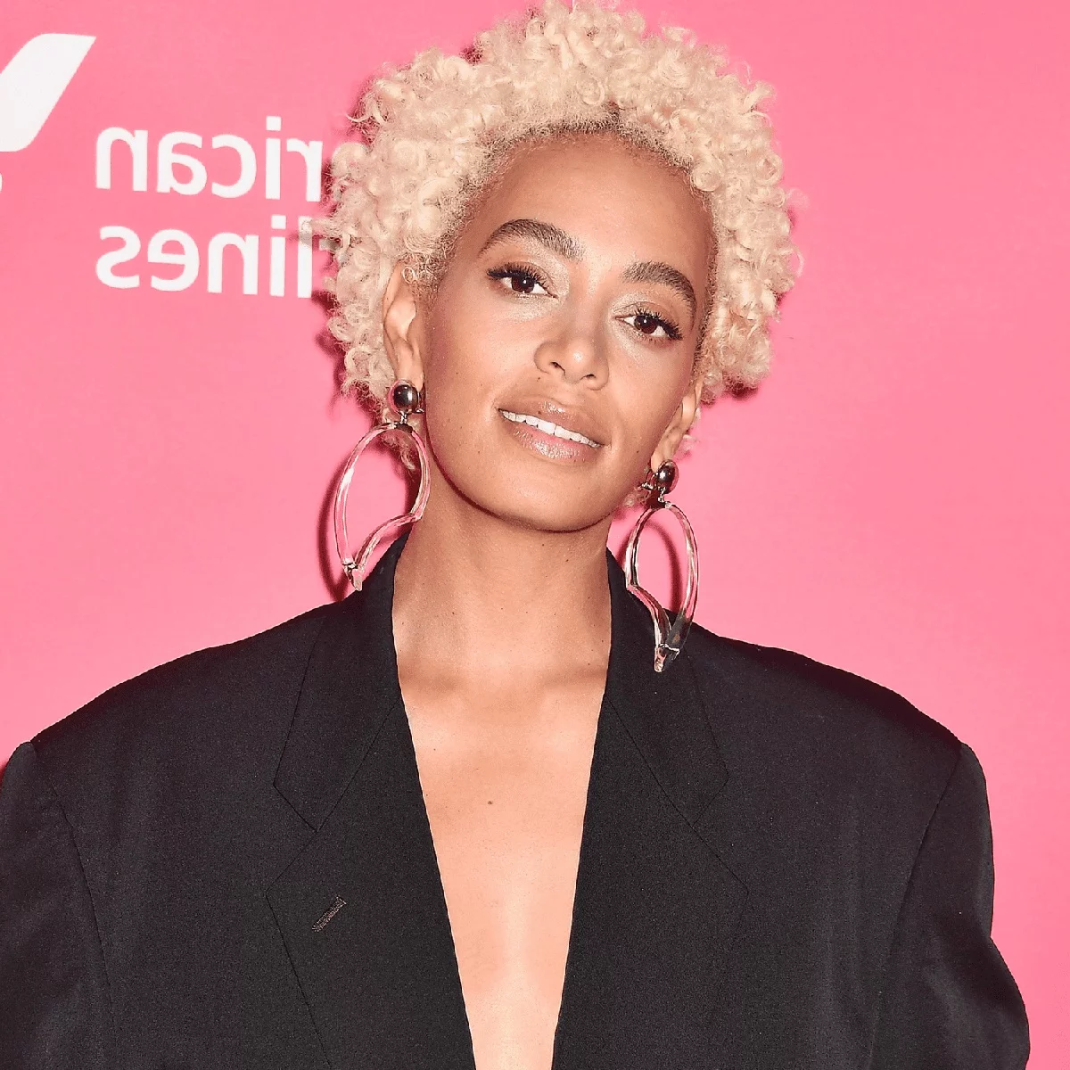 lockiges blondes Haar kurz geschnitten - junge Frau trägt Ohrringe