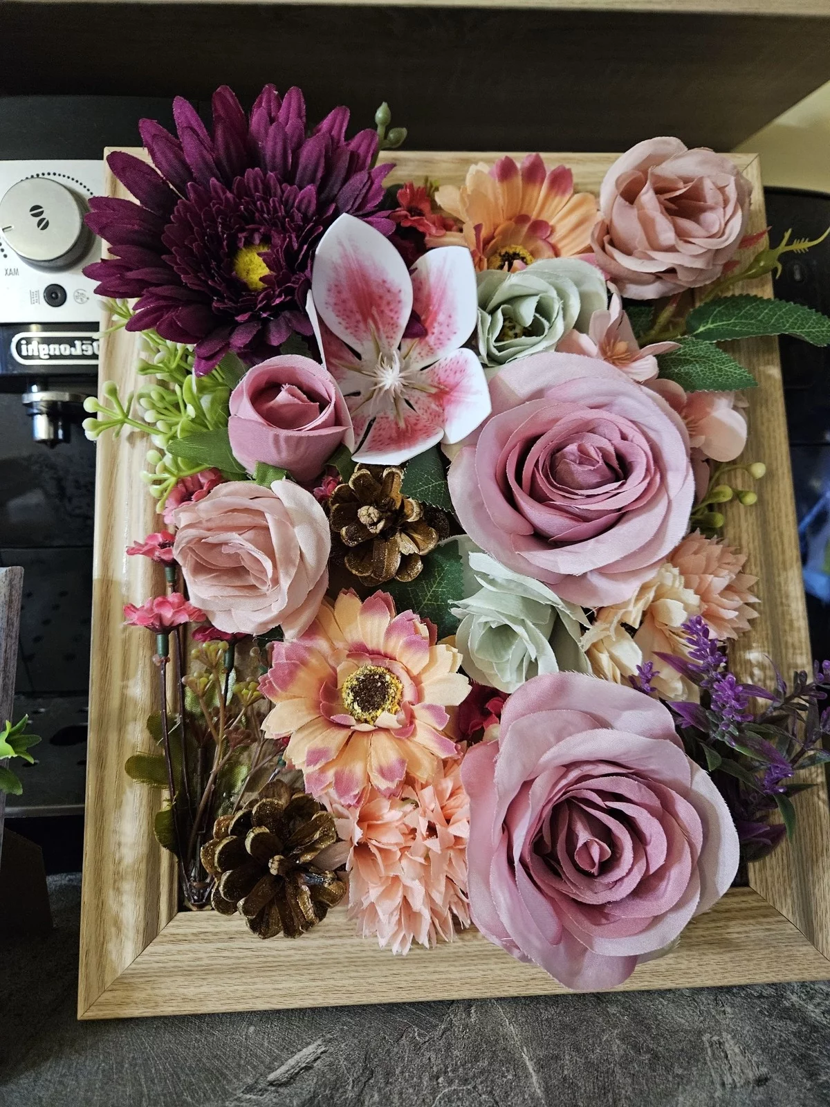 künstliche rosa Rosen und andere Blüten im Holzrahmen arrangiert