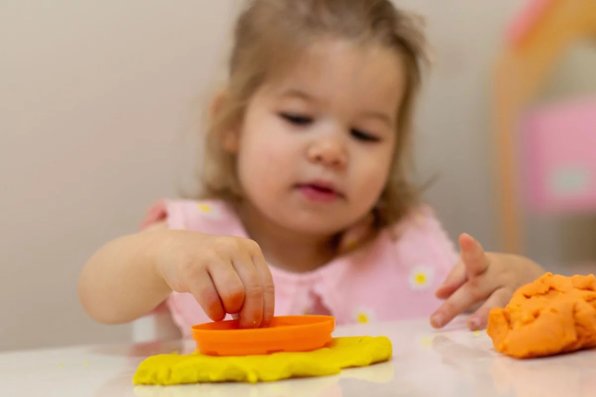 kleines Mädchen spielt mit Knetemasse - kreative Tätigkeit 