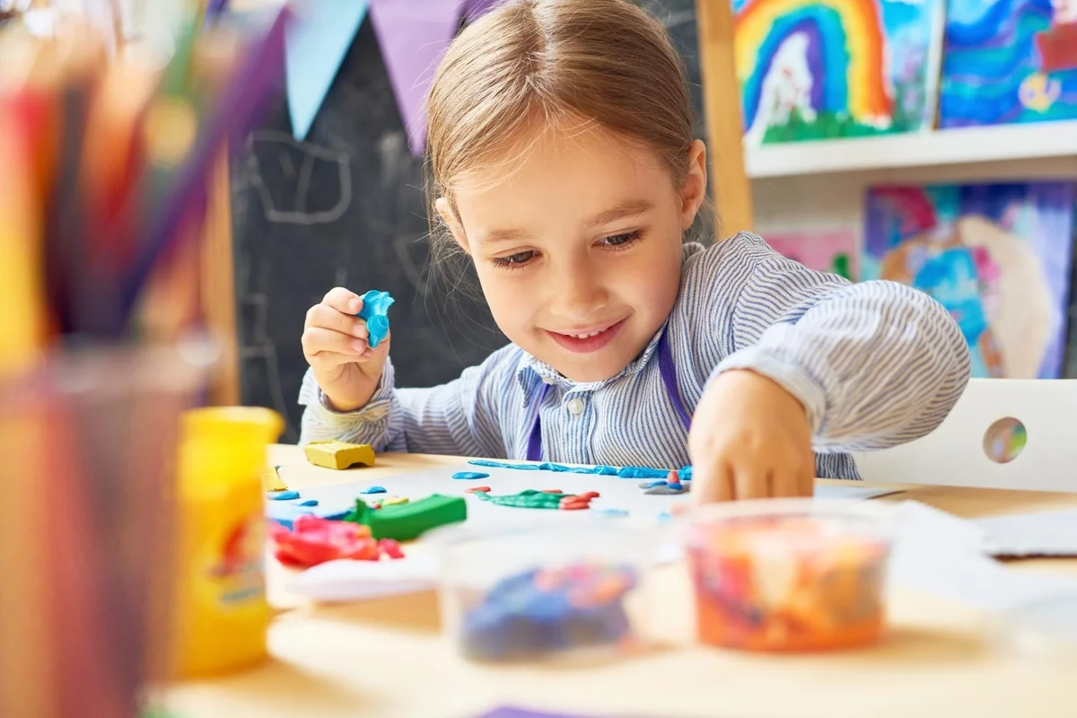 im Kindergarten spielen - kleines Mädchen spielt mit Knetemasse