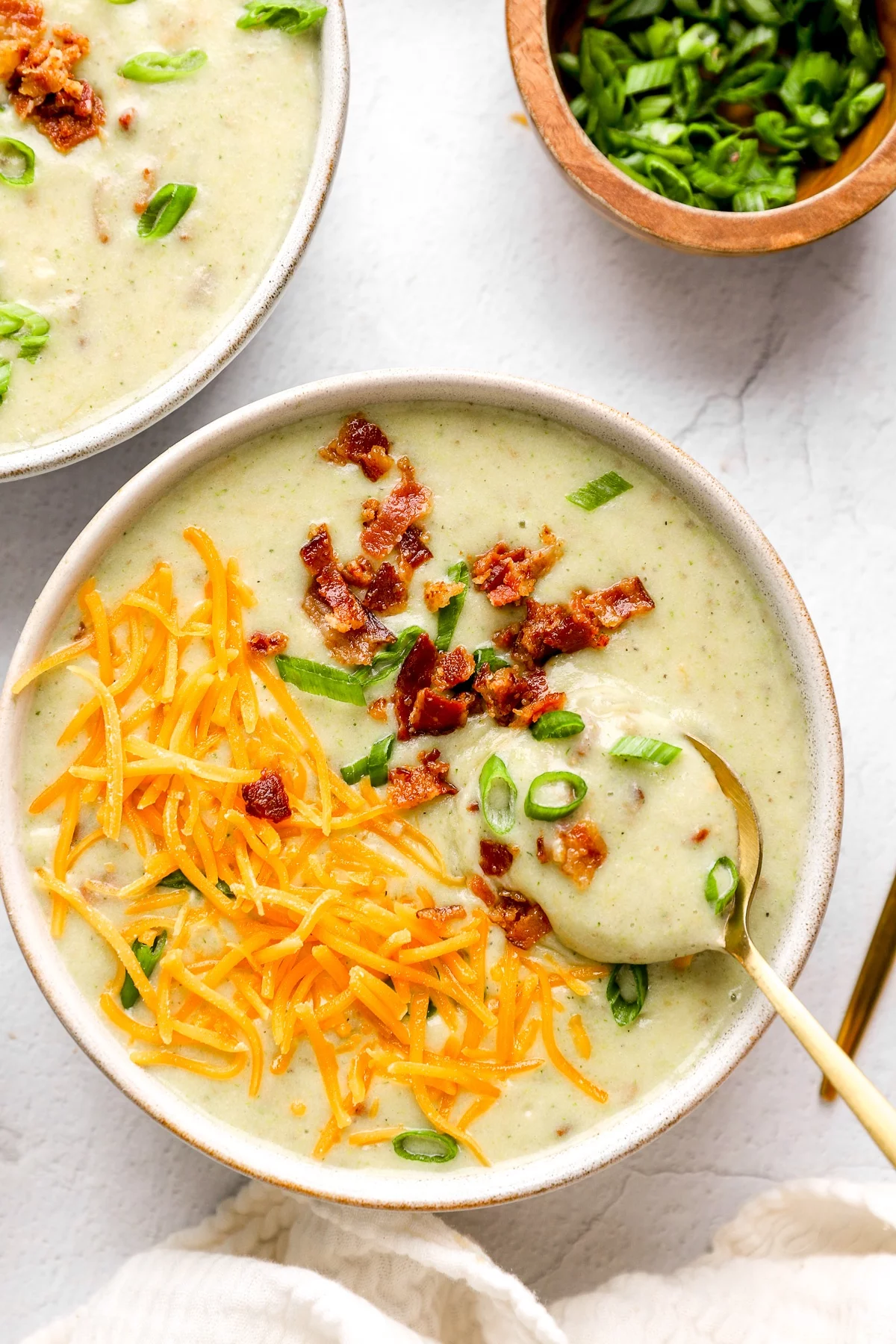 köstliche Suppe mit geriebenem Gelbkäse, Speck und frischem Schnittlauch 
