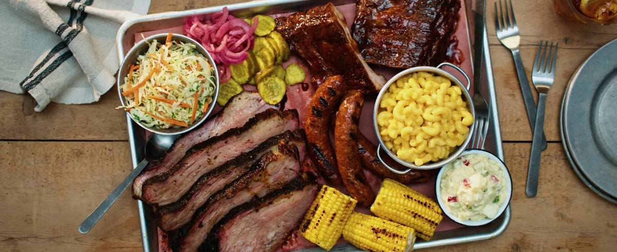 Fleisch und Bratwürste vom Grill mit Beilagen - Gemüsesalate und Korn 