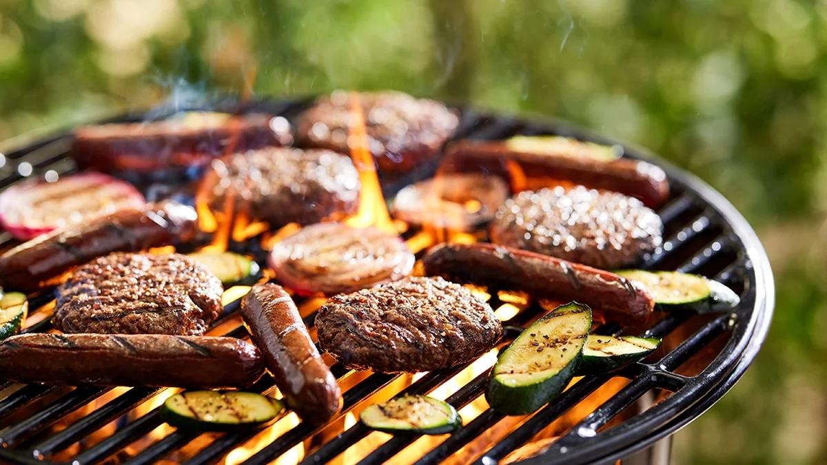 Bratwürste, Bouletten und Zucchini Scheiben auf dem Grill 