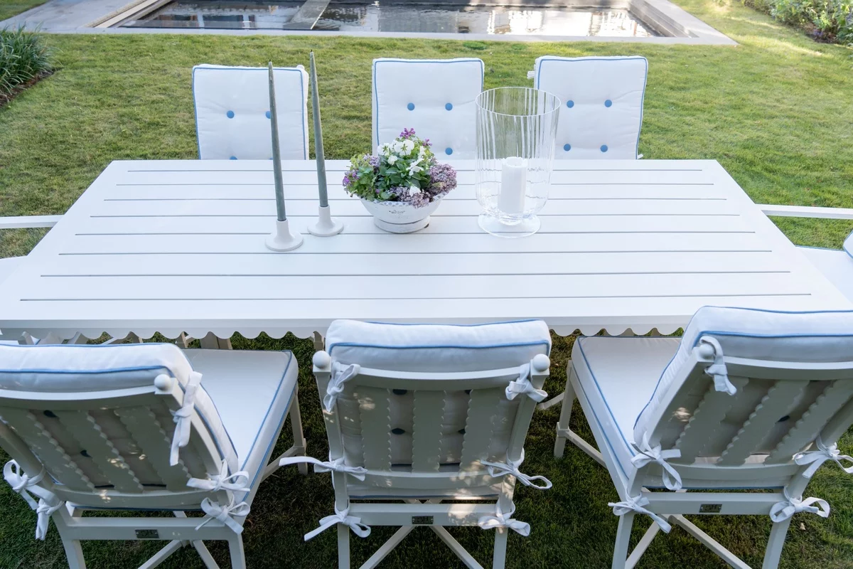 weißer Holztisch im Freien mit Kerzen und Blumen dekoriert