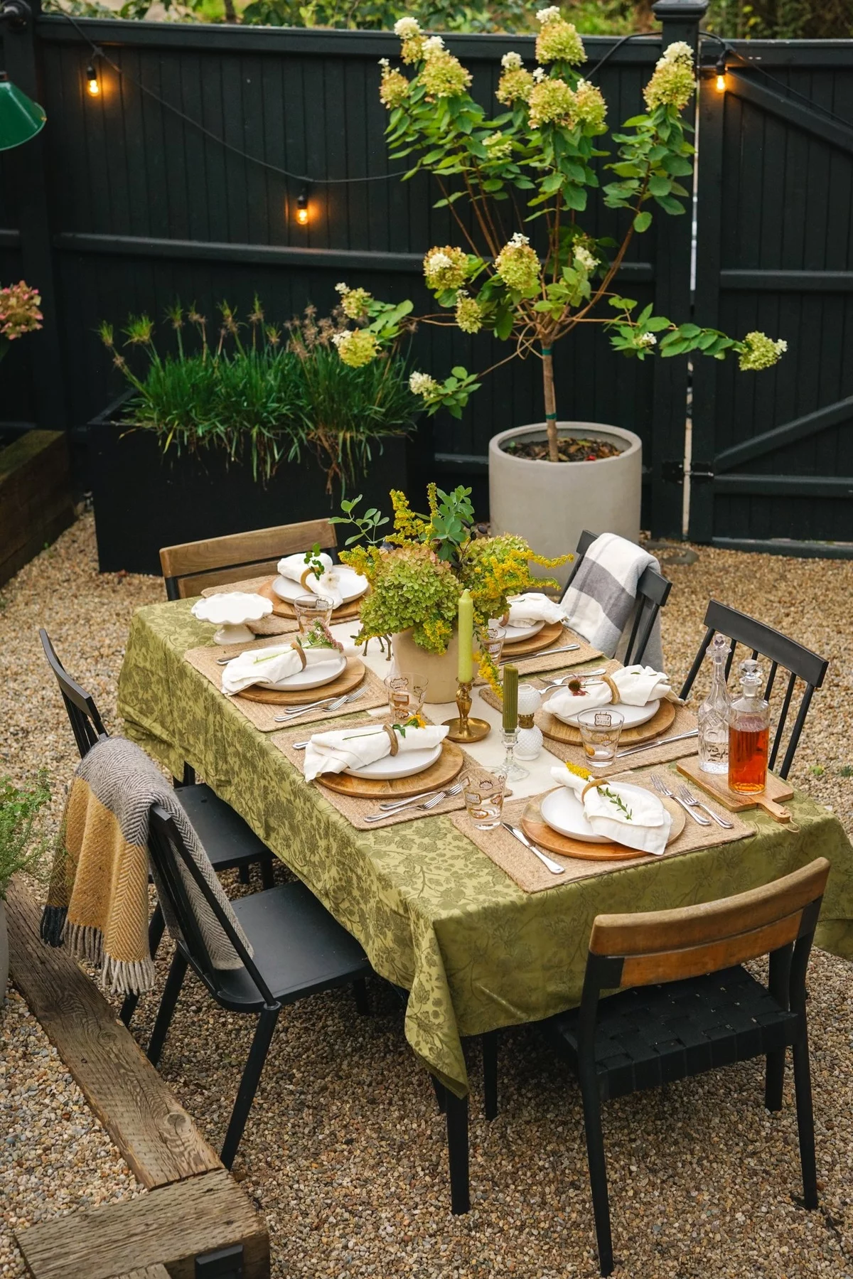 gedeckter Tisch im Freien mit kerzen und Vase mit grünen Zweigen dekoriert