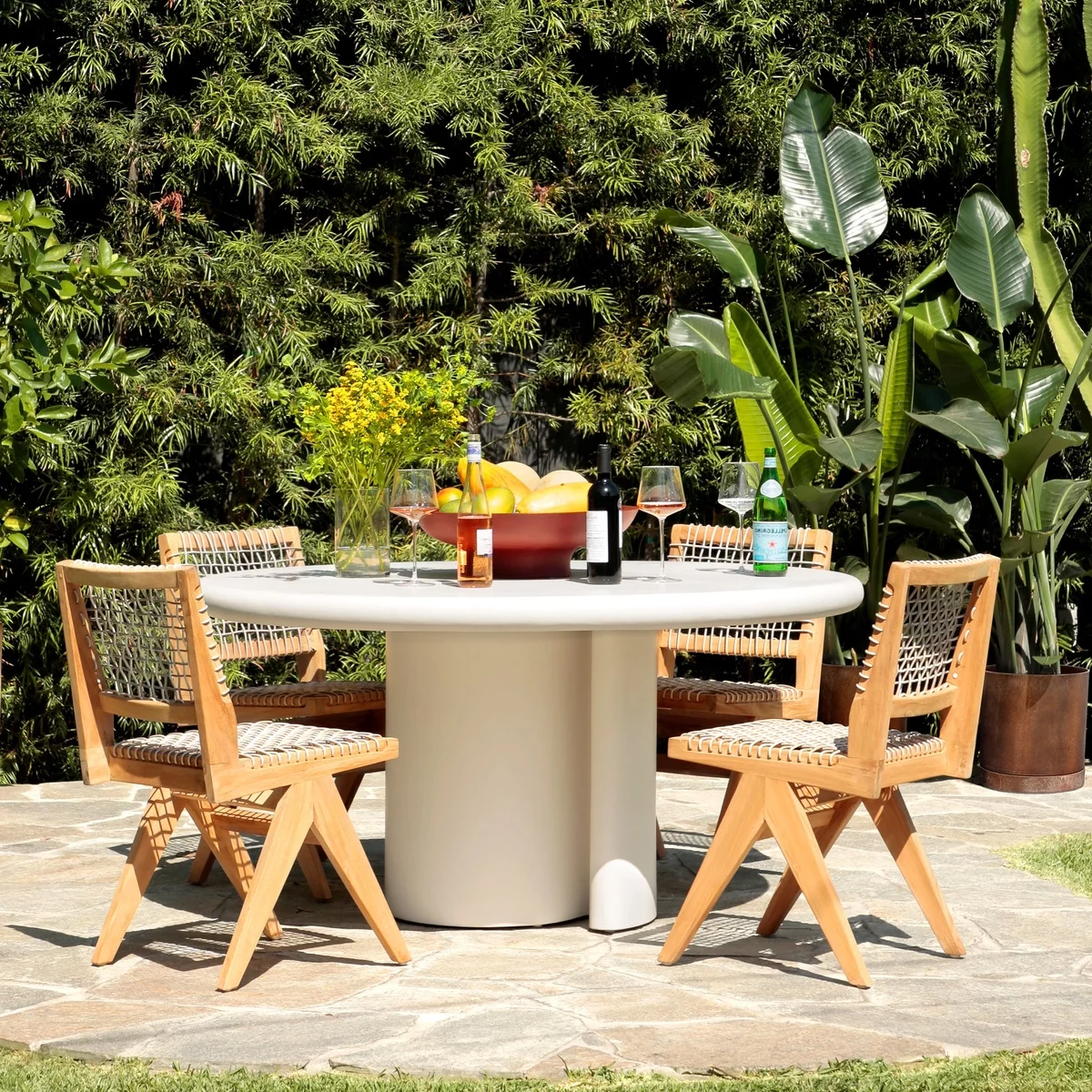 runder Terrassentisch mit einer Schüssel mit Obst und Weinflaschen 