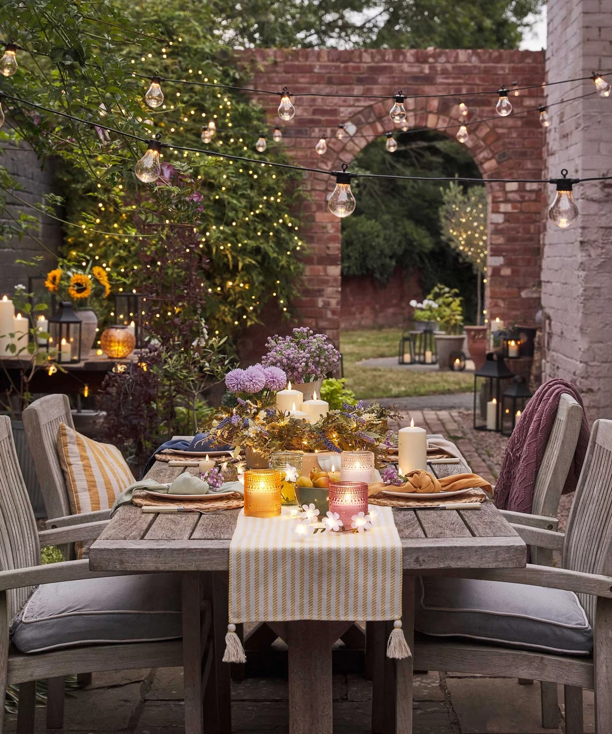 schöne Deko Terrassentisch mit Blumen, Kerzen und Licherketten 