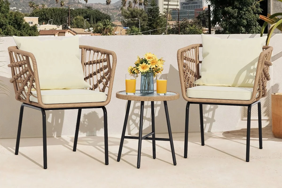 kleiner runder Tisch zwischen zwei Stühlen mit einer Vase mit gelben Blumen dekoriert