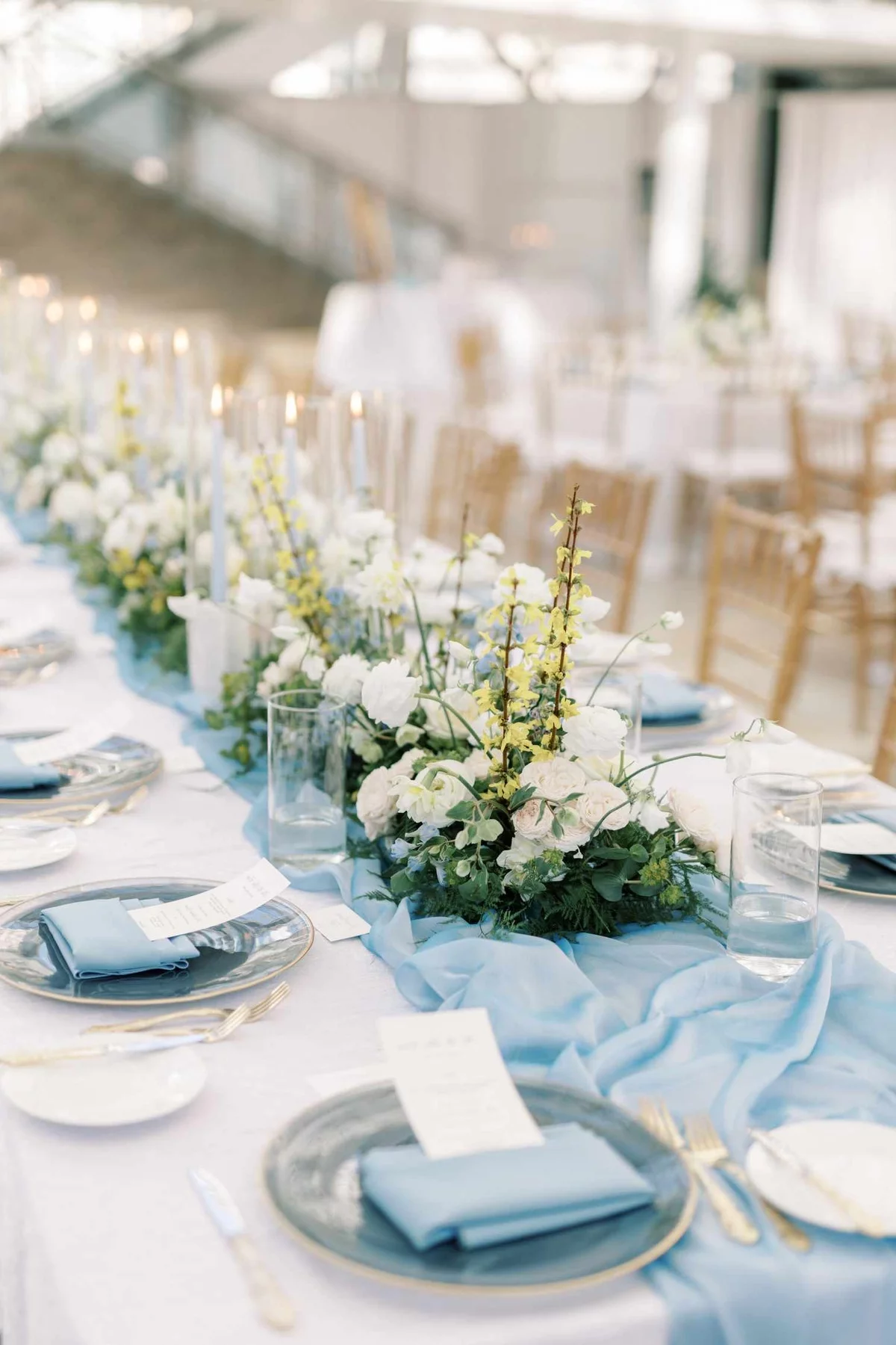 weiße Rosen und kleine Zweige mit gelbe Blüten in der Tischmitte