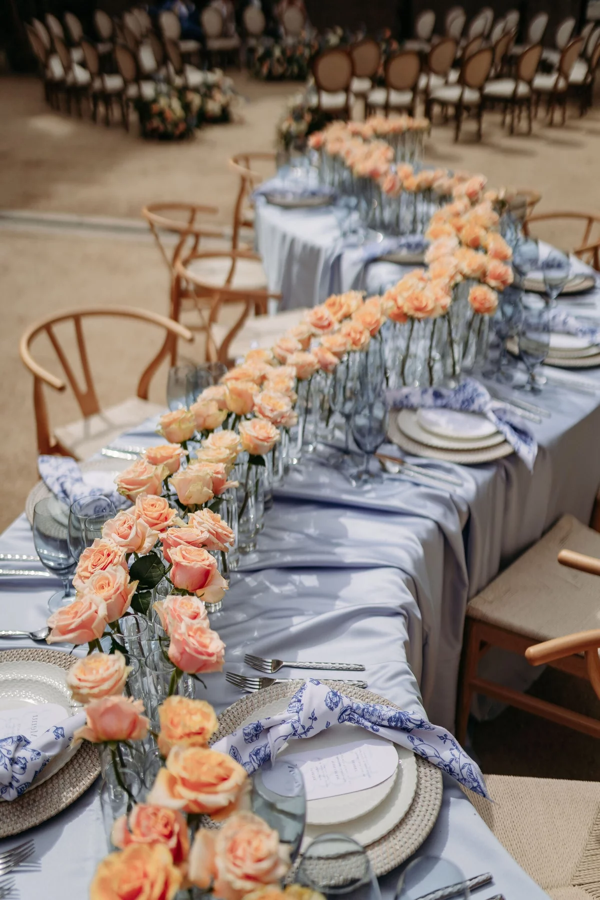 orangenfarbene Rosen schmücken einen langen Hochzeitstisch 