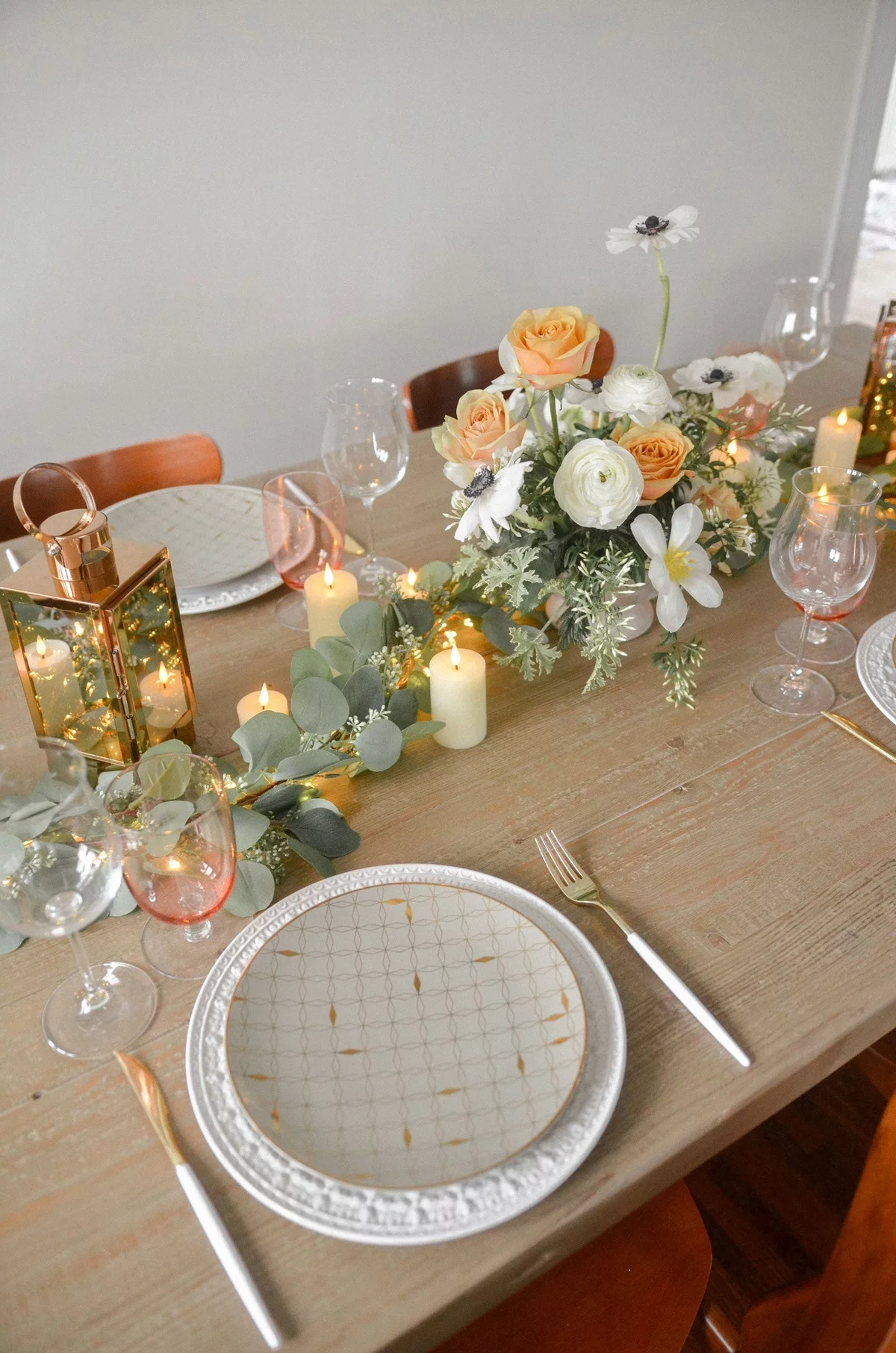 brennende weiße Kerzen und Blumen in der Tischmitte