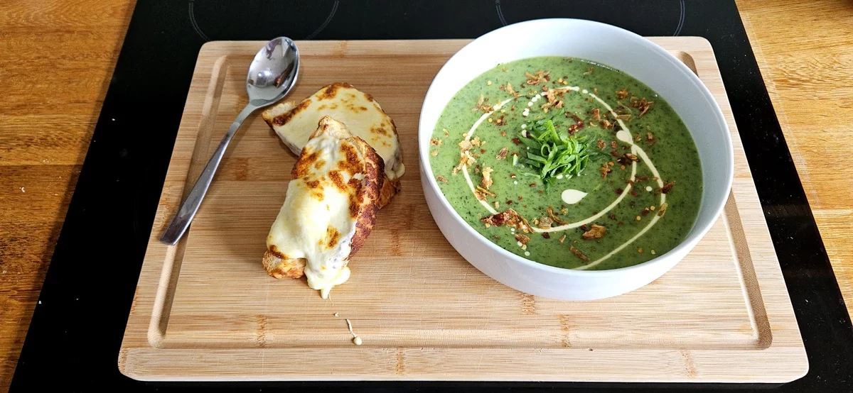 gesunde Bärlauchsuppe mit zwei getoasteten Scheiben Brot auf einem Brett serviert