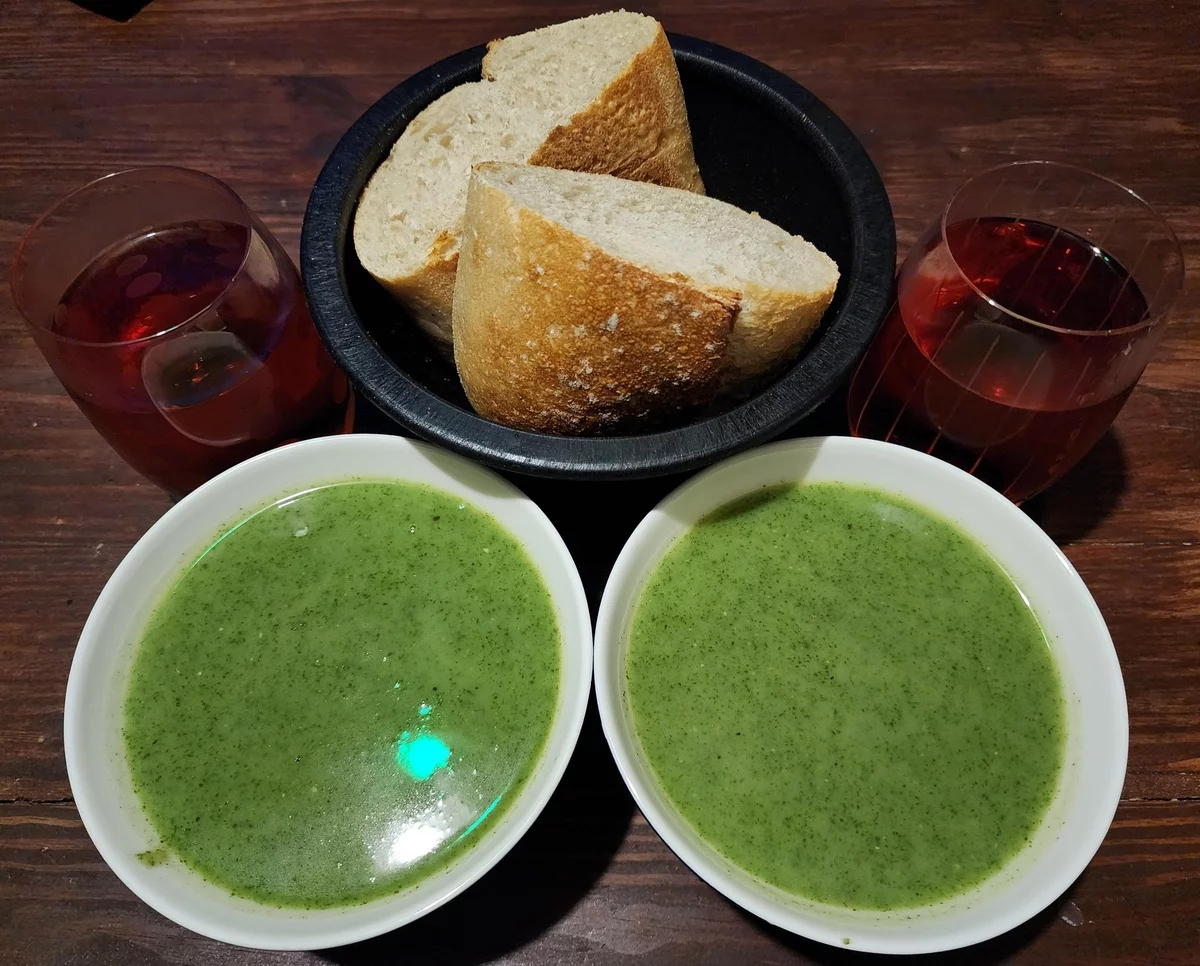 zwei Suppenteller mit Bärlauchsuppe mit frischem Brot daneben