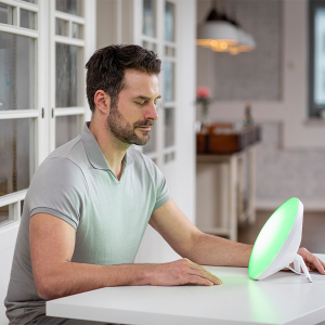 Ein Mann nutzt eine Tageslichtlampe mit grünem Licht