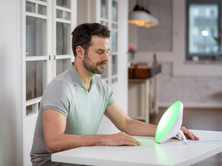 Ein Mann nutzt eine Tageslichtlampe mit grünem Licht