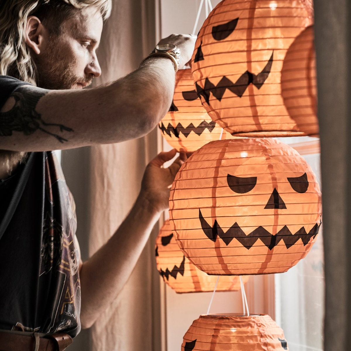 Junger Mann dekoriert das Fenster mit Papierlaternen