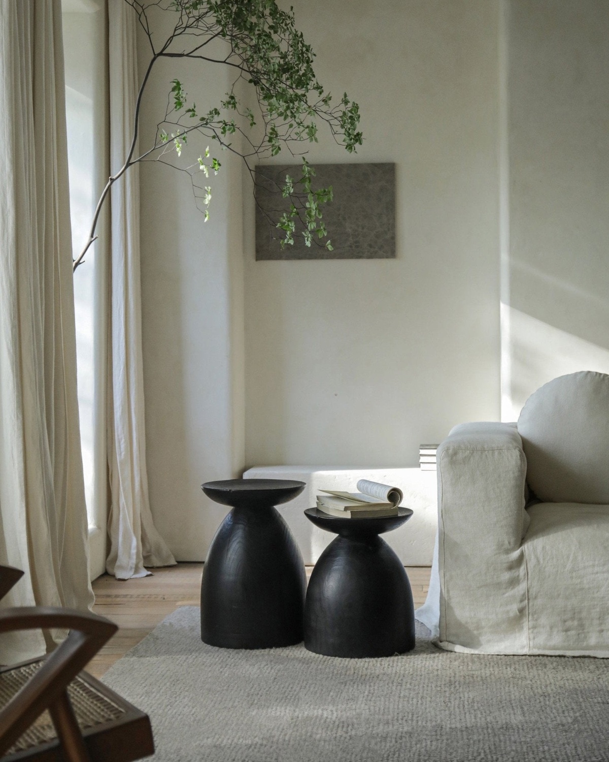 zwei schwarze Beistelltische im weißen Wabi Sabi Wohnzimmer