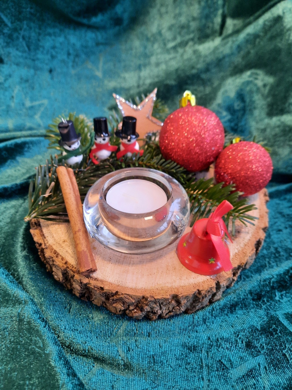 Weihnachtsdeko mit Holzscheiben - eine Kerze, Zimtstangen, zwei rote Kugeln 