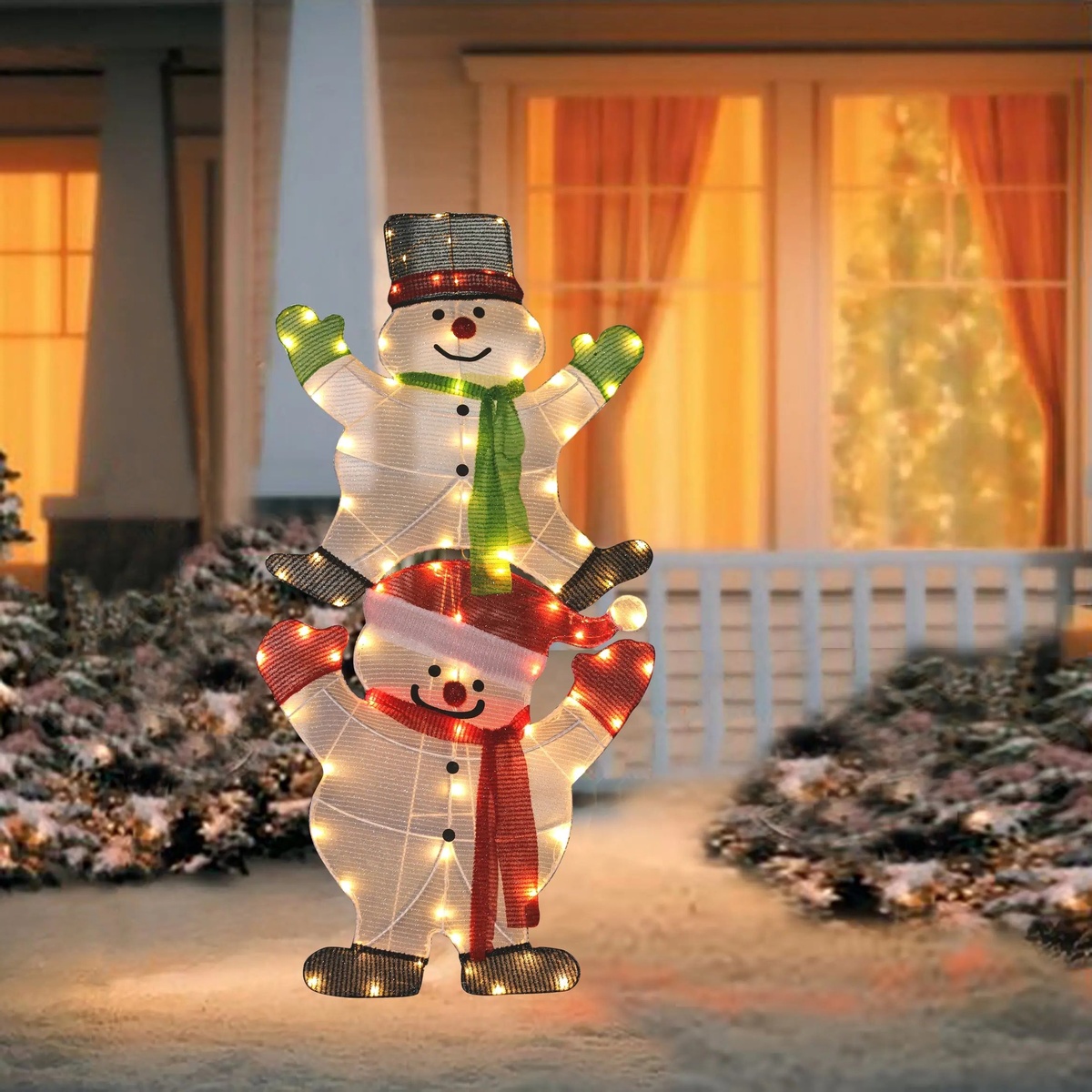 zwei lustige leuchtende Schneemänder vor dem haus