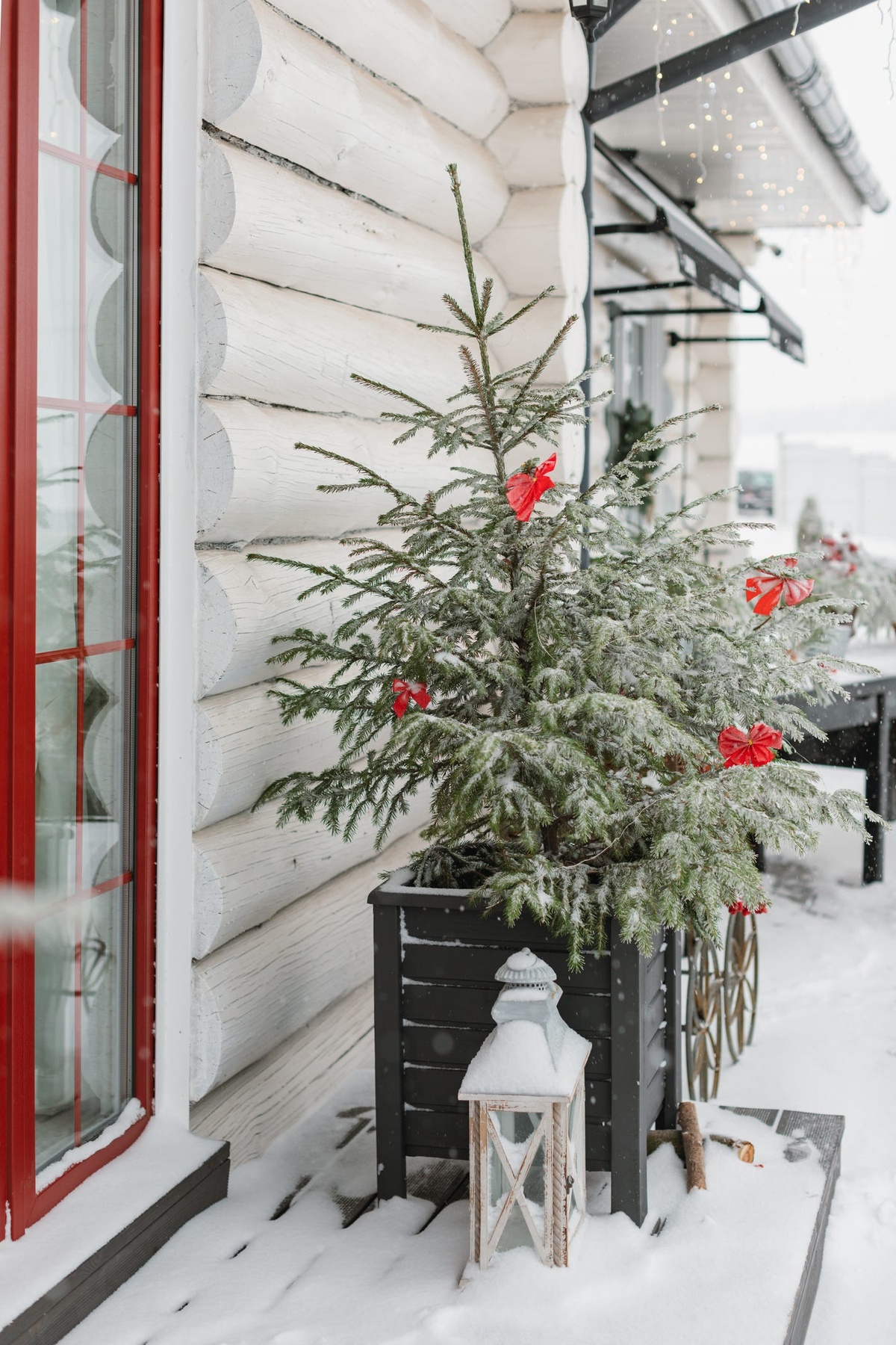 Tannenbaum mit wenig Deko vor dem Eingang Laterne und viel Schnee
