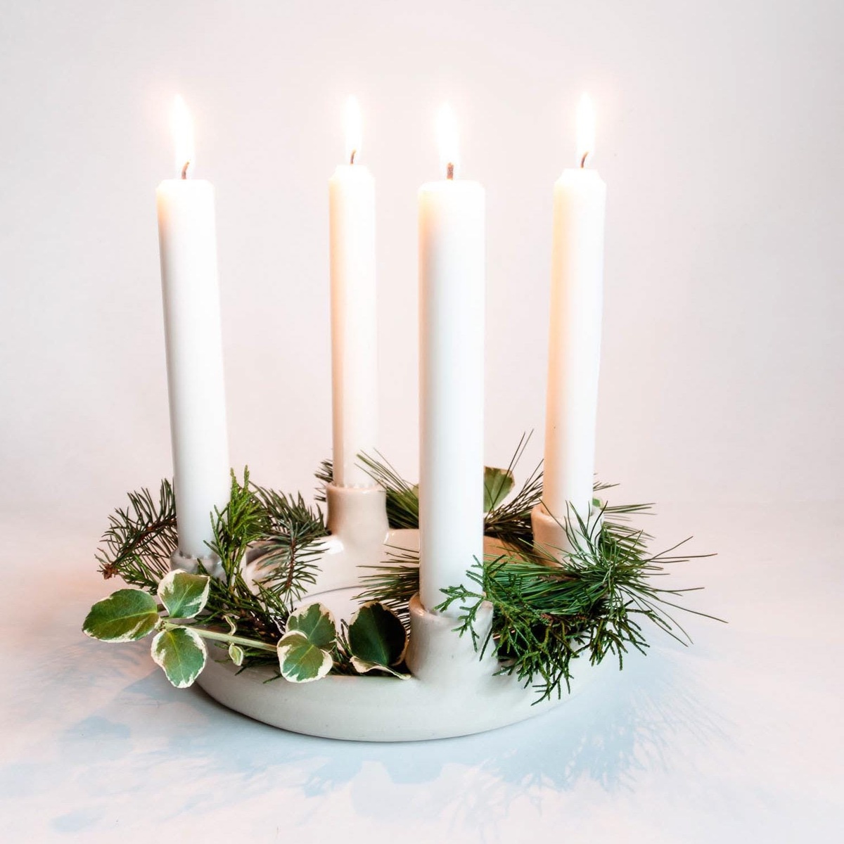 minimalistischer Adventskranz mit Tannengrün und vier weißen Kerzen 
