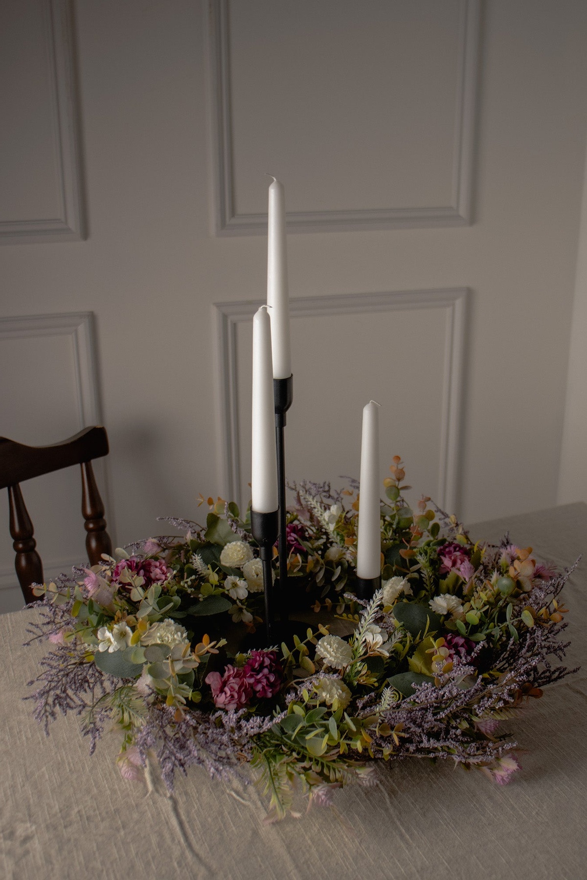 drei weiße Kerzen mit Blüten rundherum 