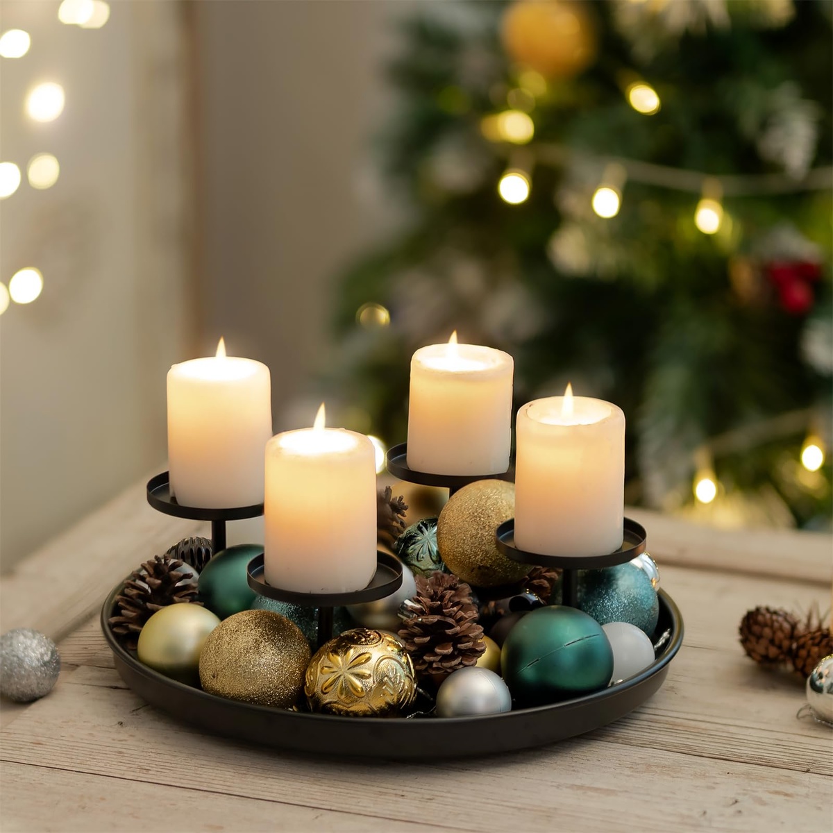 vier weiße Kerzen auf Tablett mit Weihnachtskugeln rundherum 