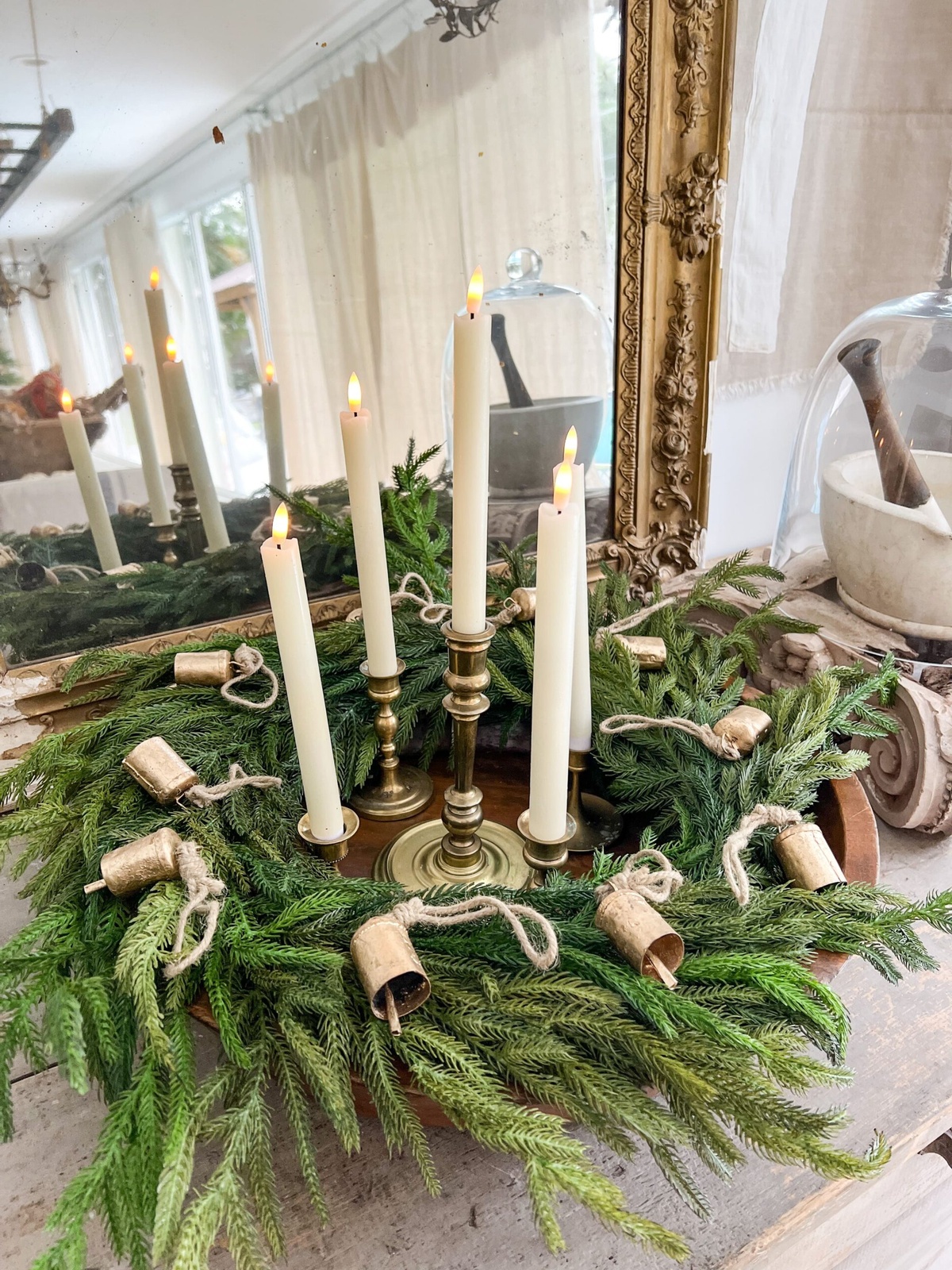 rustikales Arrangement mit vier weißen Kerzen und viel Tannengrün 