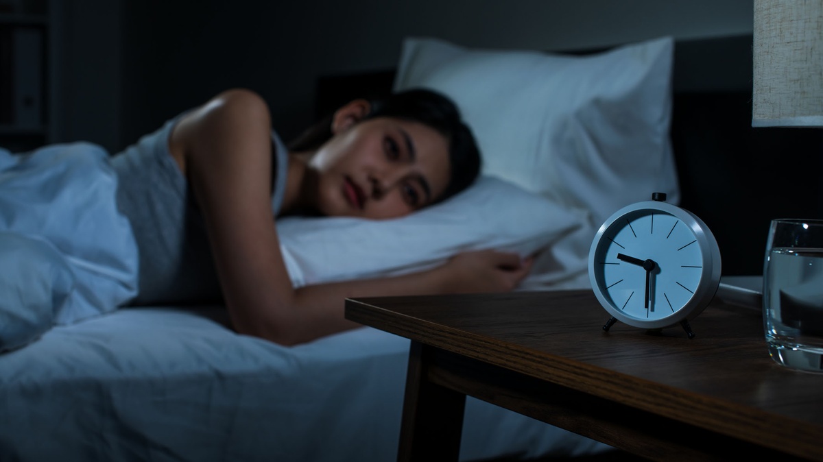 junge Frau liegt im Bett ohne einzuschlafen