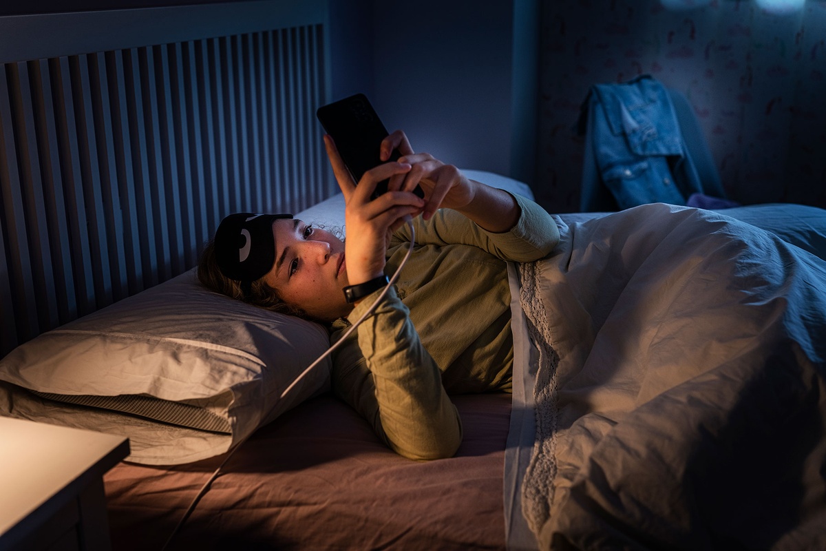 junge Frau mit Handy im Bett