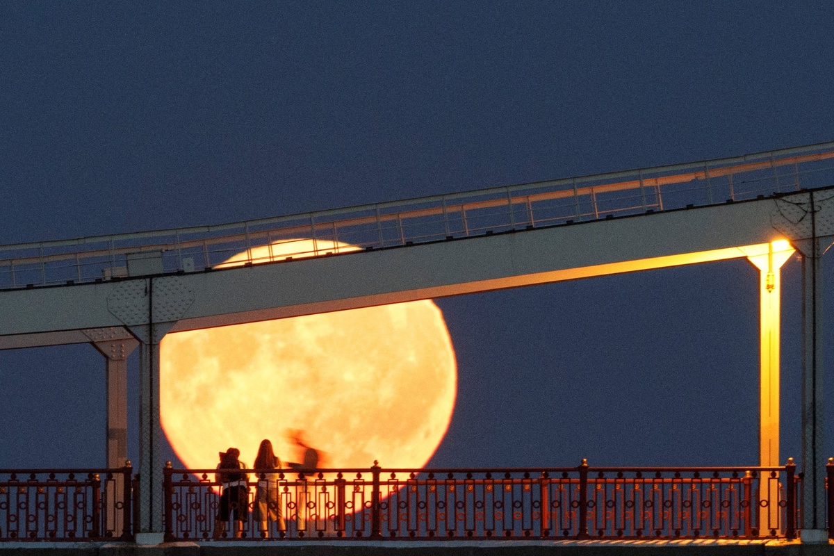 junge Leute betrachten den Vollmond von einer Brücke