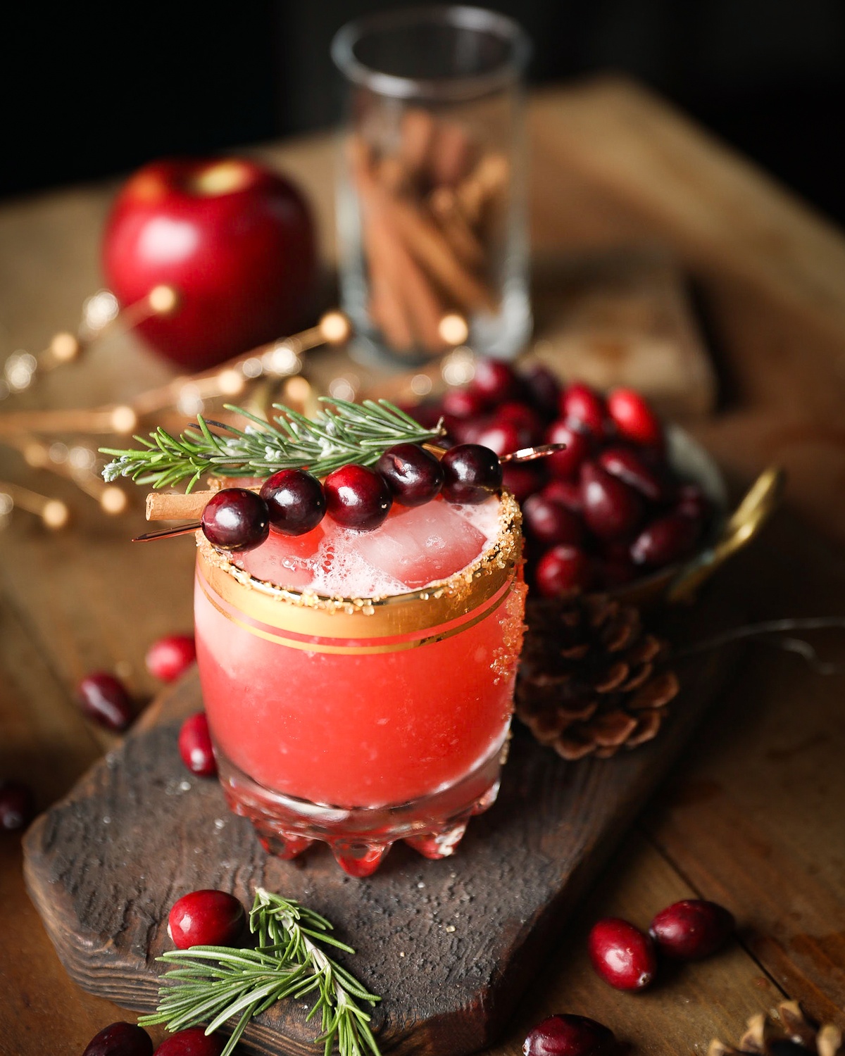 Cranberrys, Apfel und Zimtstangen mit Rosmarin dekoriert