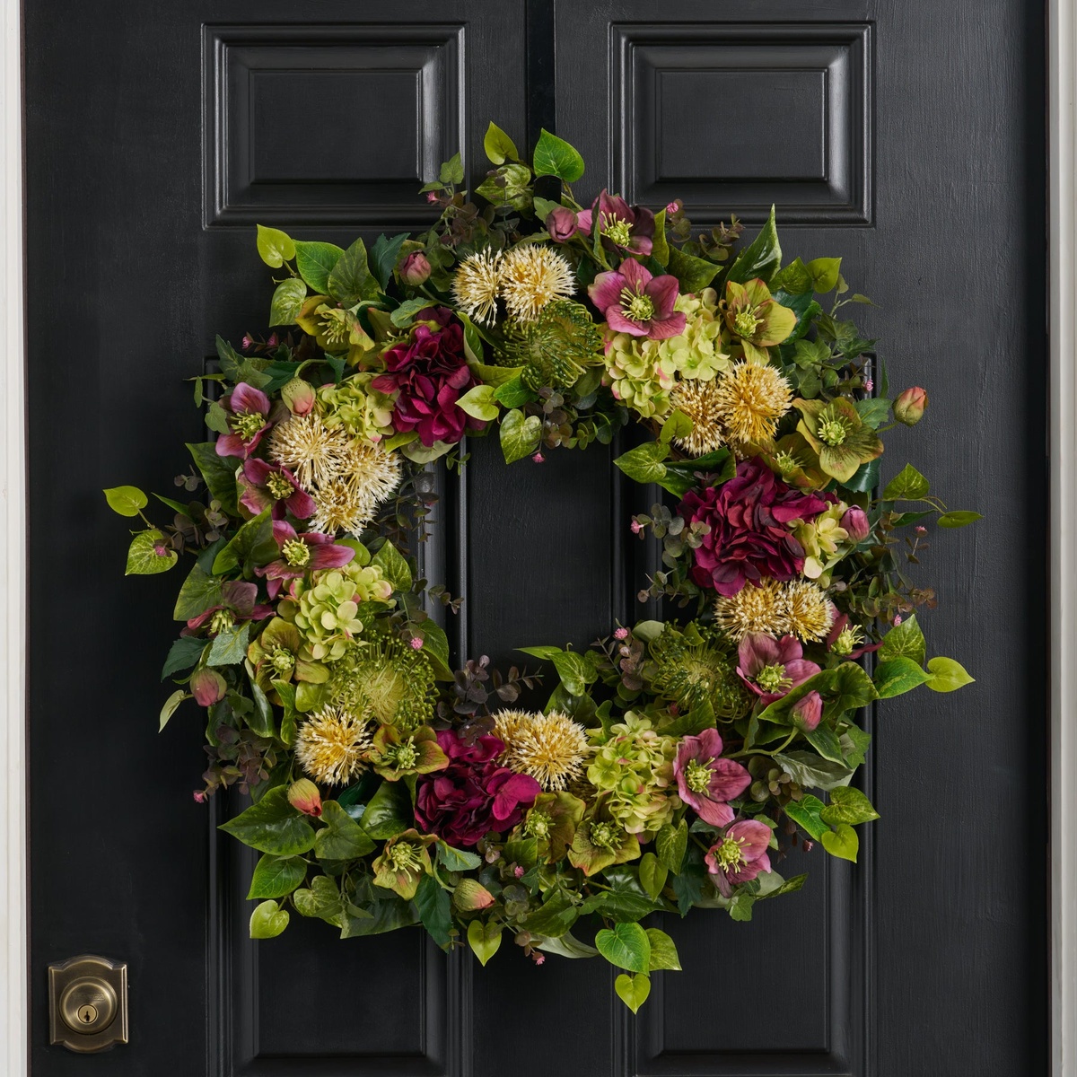 Weihnachtskranz mit verschiedenen Winterblumen an der Eingangstür