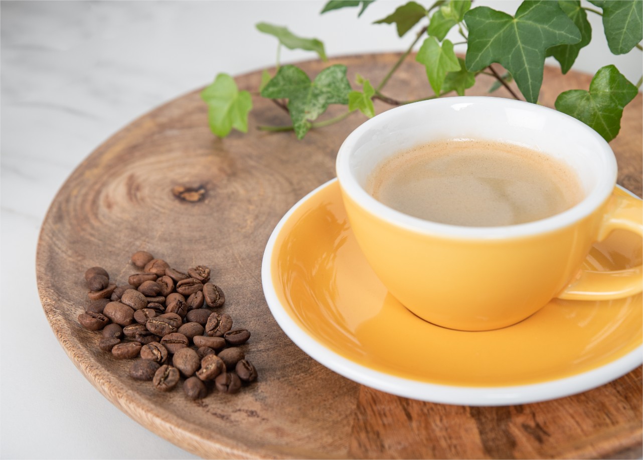 Tasse Kaffee und Kaffeebohnen auf einem Holztablett