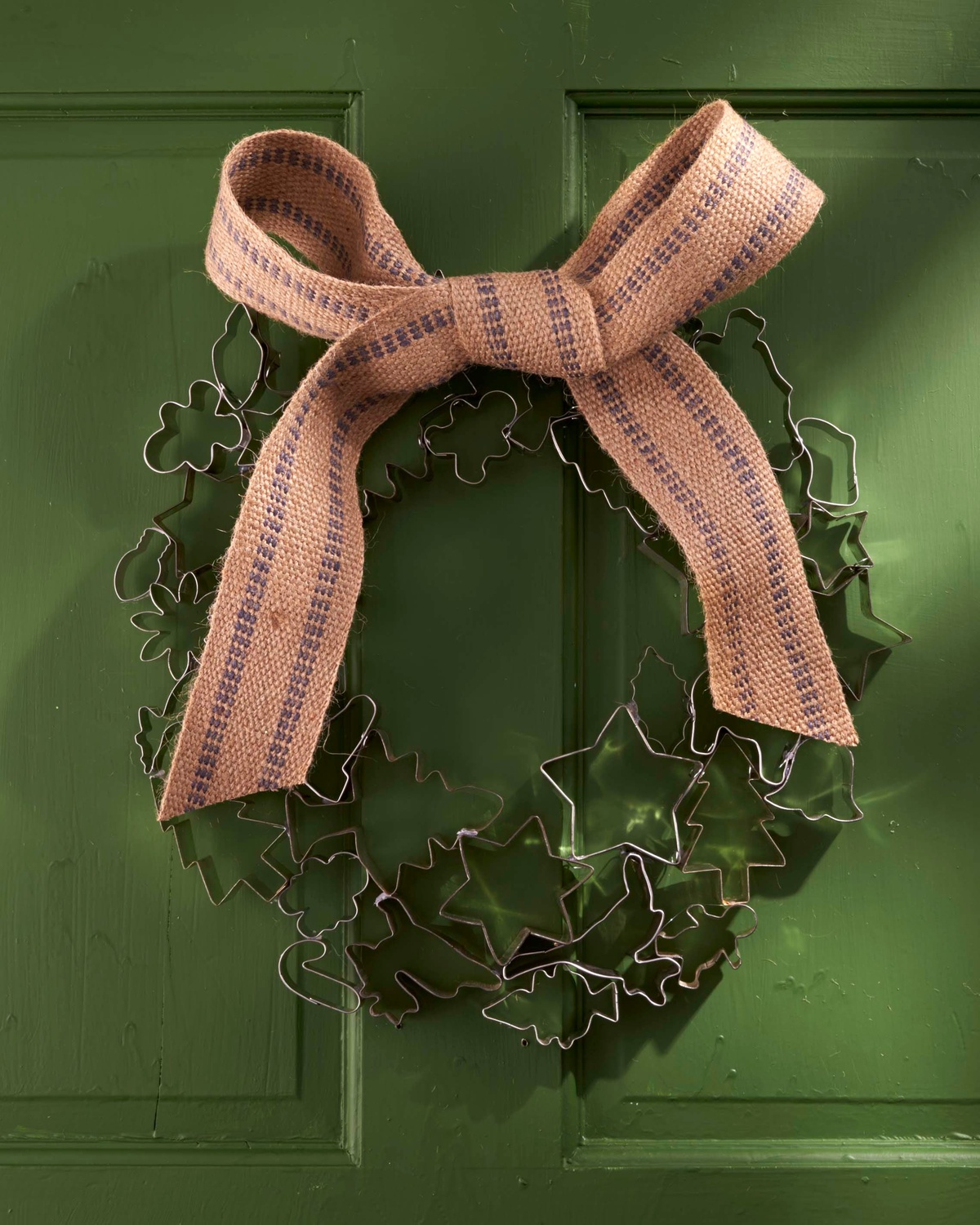 eine große beigefarbene Schleife schmückt den Kranz aus Metallfiguren 