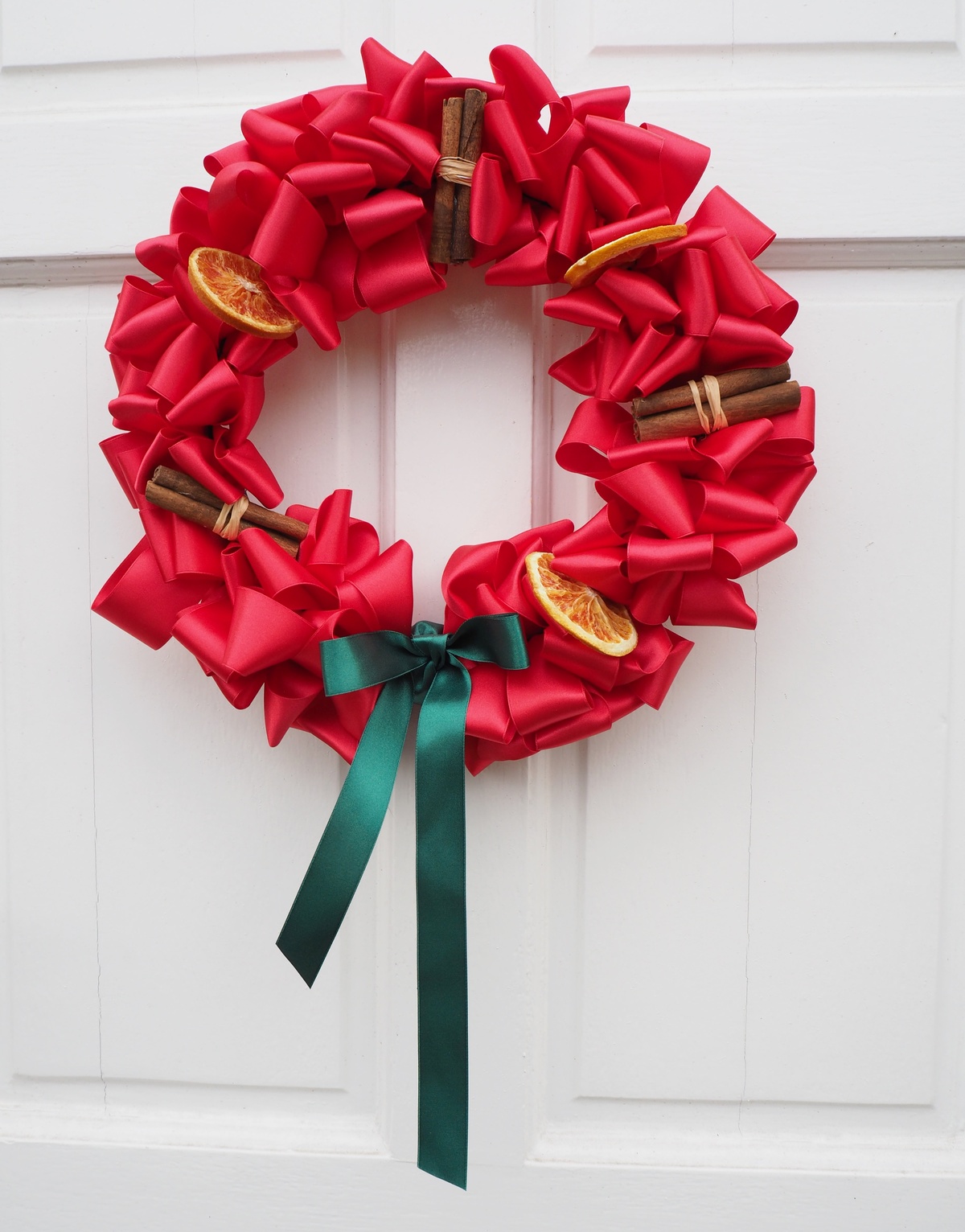 Zimtstangen und rote Schleifen dekorieren den Weihnachtskranz 
