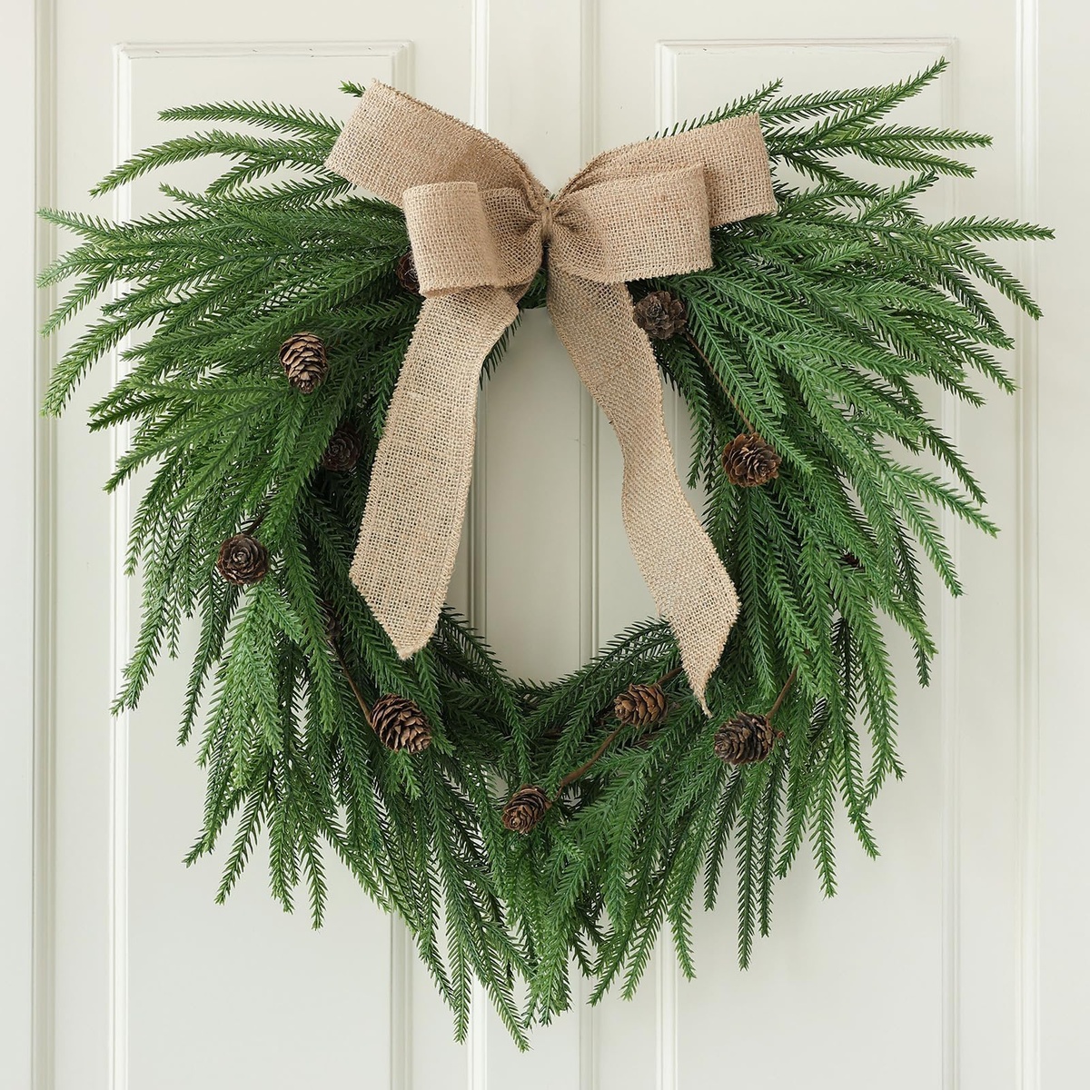 grüne Zweige, Zapfen und eine beigefarbene Schleife 