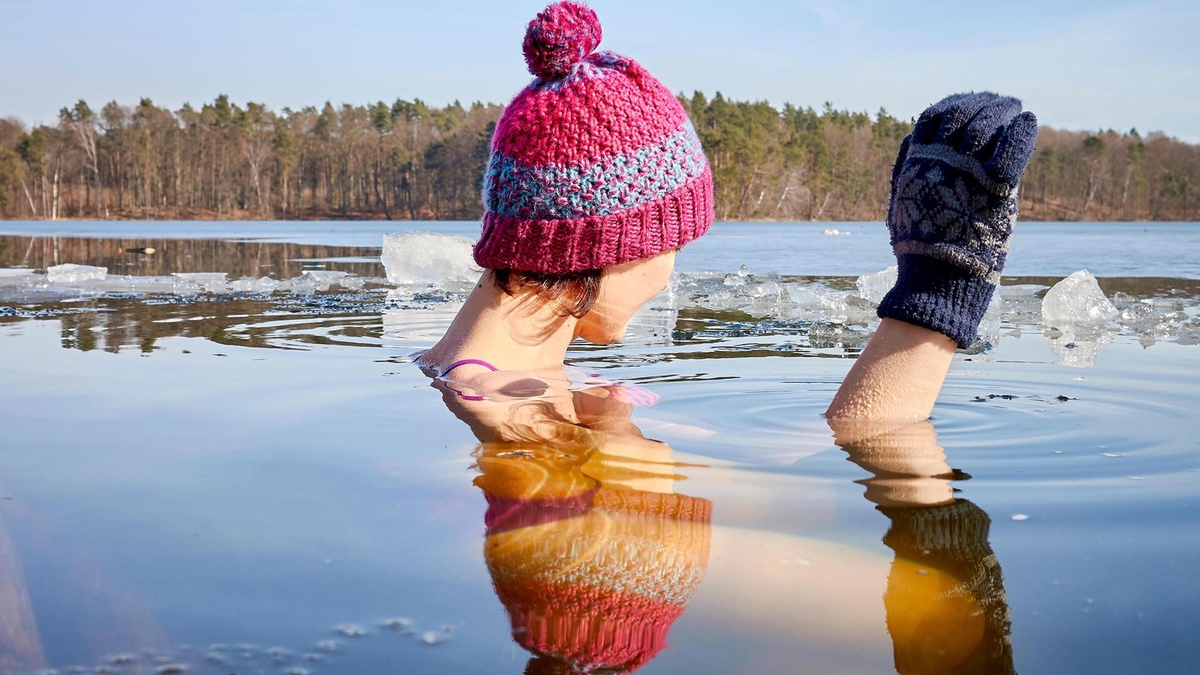 junge Frau trägt Mütze und Handschuhe beim Winterbaden