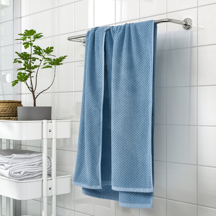 ein blaues Duschtuch hängt im weißen Bad 