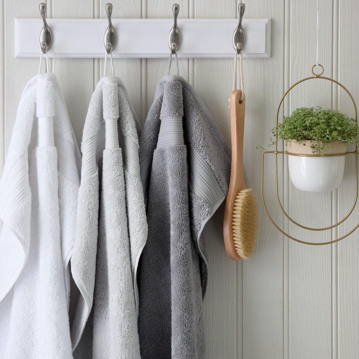 drei Duschtücher in dezenten Farben hängen im Bad 