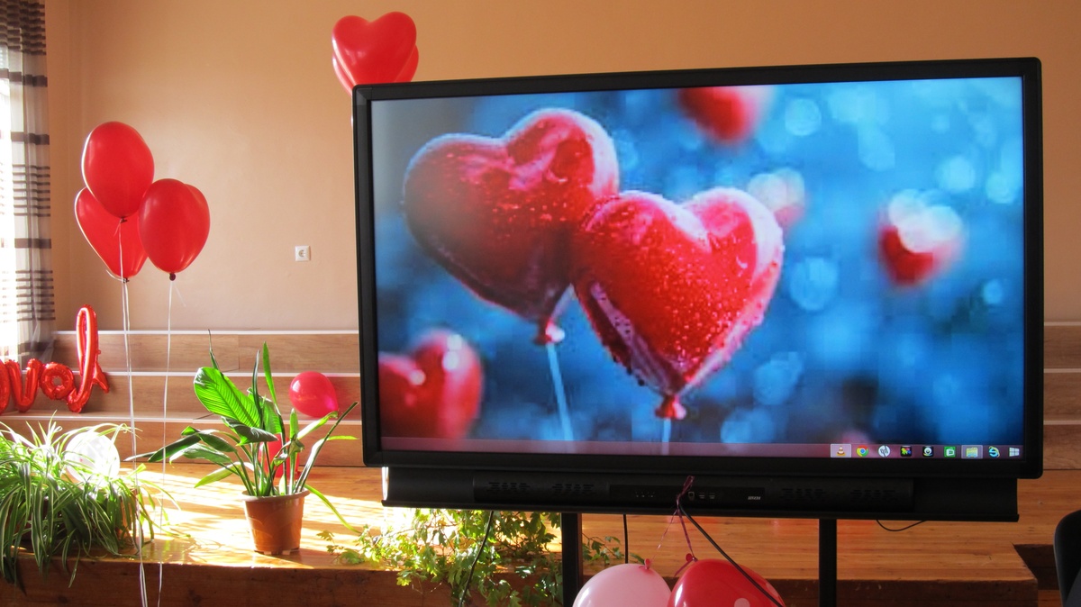 auf dem Bildschirm Ballons in Herzform, in der Raumdeko viele rote Akzente